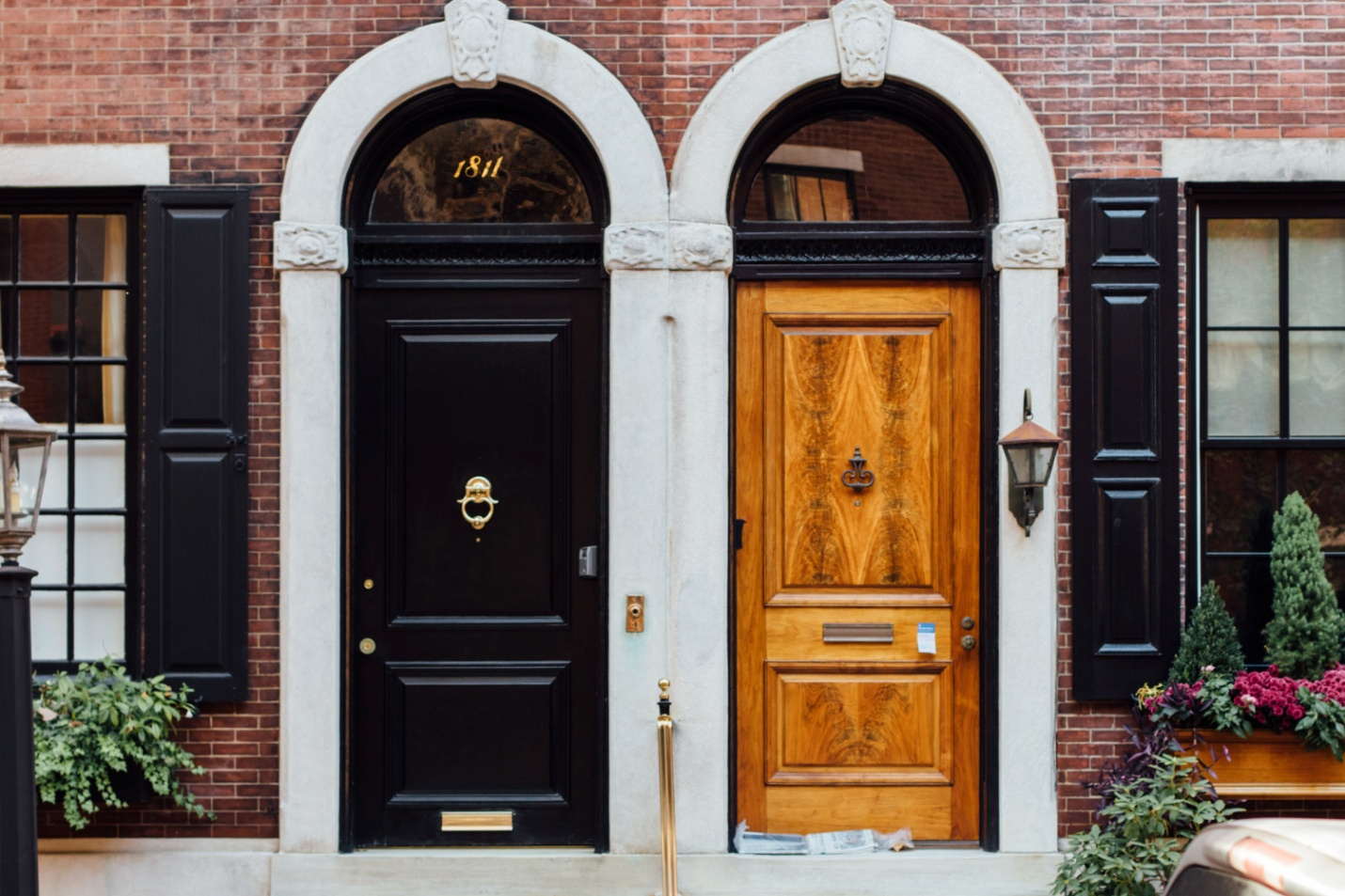 A couple of dark and light wooden doors with knockers attached to them